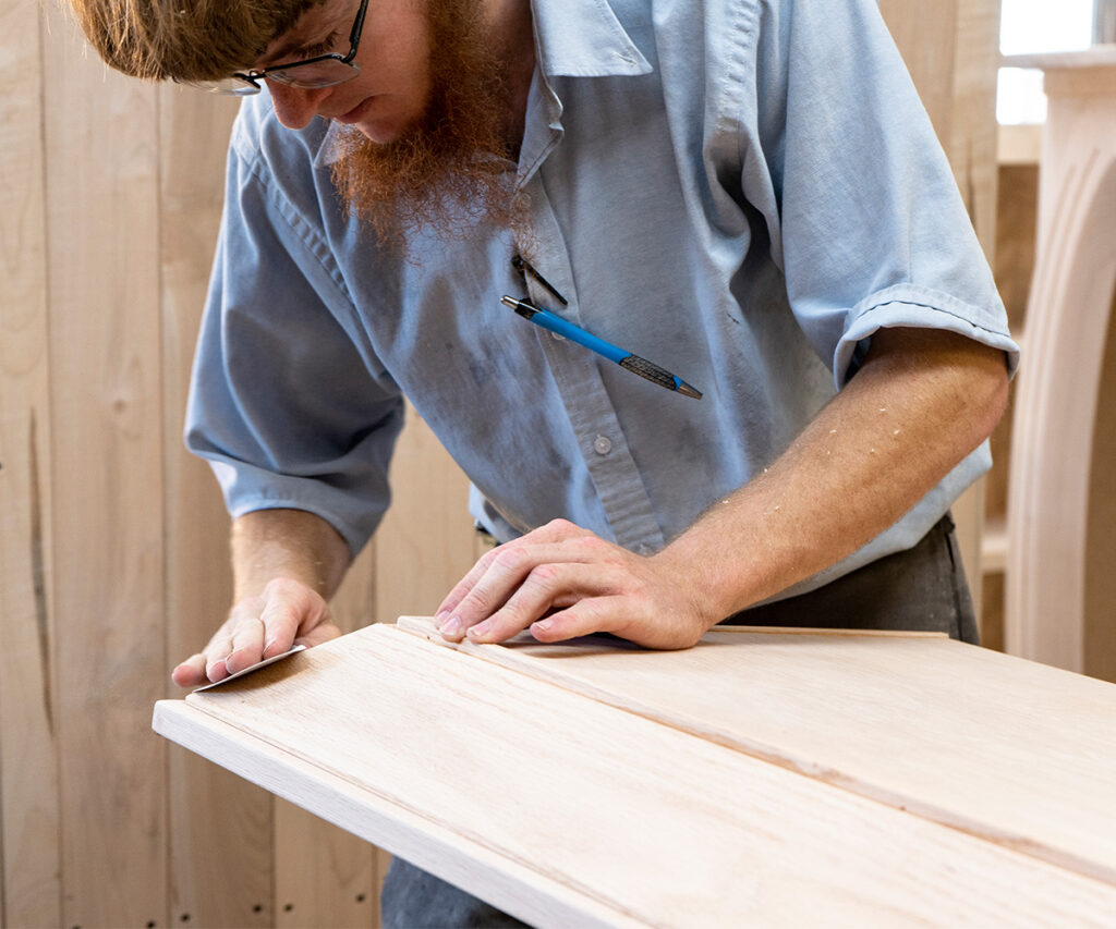  An amish craftsman carefully hand sanding a piece of furniture